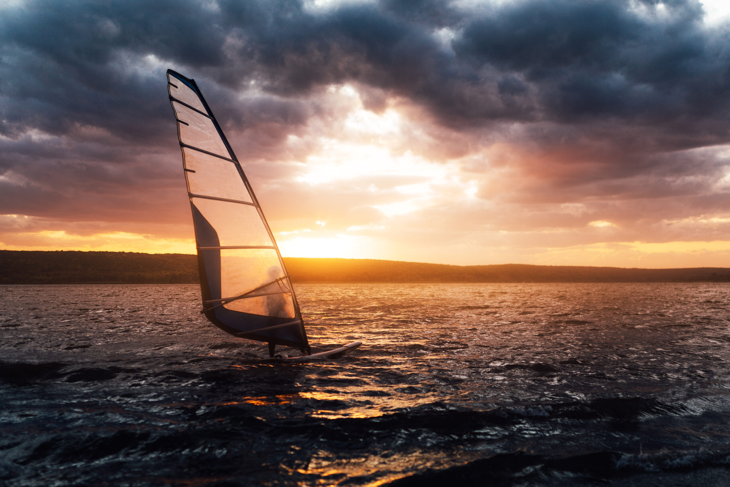 Windsurfing on a lake at sunset, contrast scene.